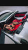 Sadie Nelson wearing a Black Heart black silk lingerie set, photographed in a red leather interior of a white Ferrari, luxury lingerie campaign image.